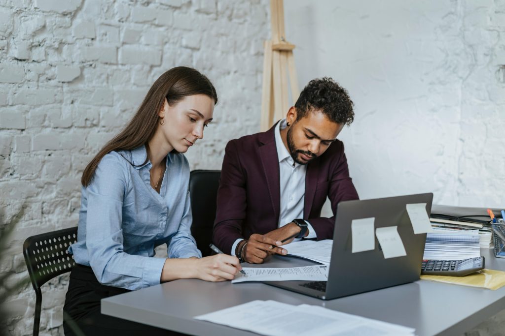 Two professionals working together at a desk in a modern office environment.