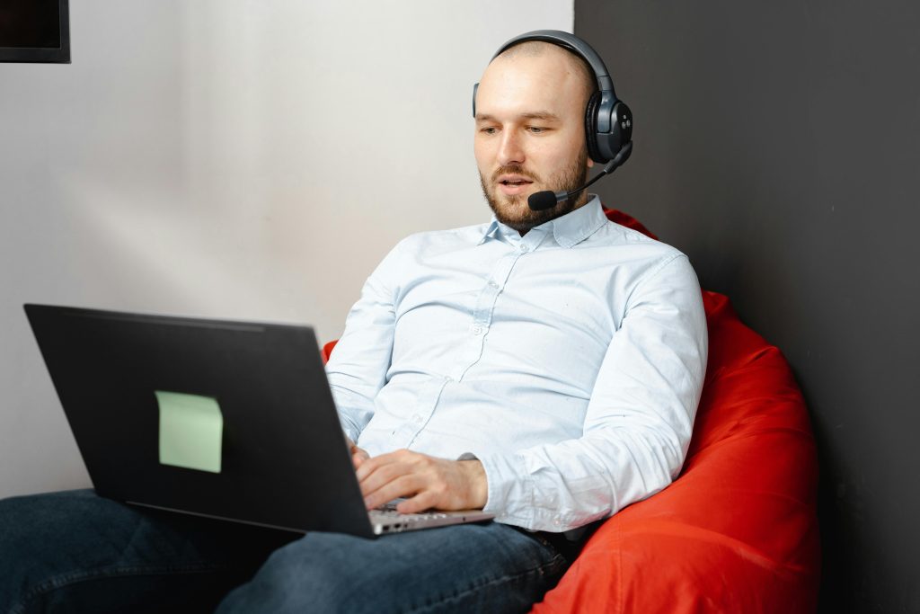 Call center agent working remotely on a laptop with headset and microphone for customer service.